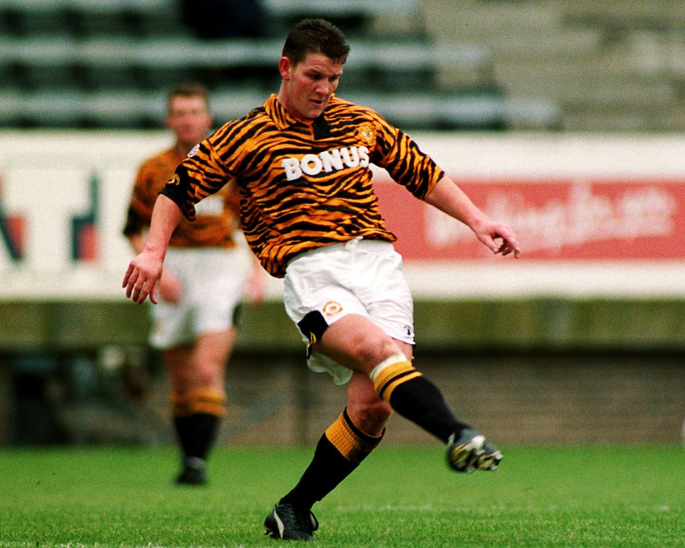 Dean Windass of Hull City in a tiger-striped jersey kicking a soccer ball.