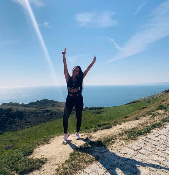 Woman celebrating on a coastal path.