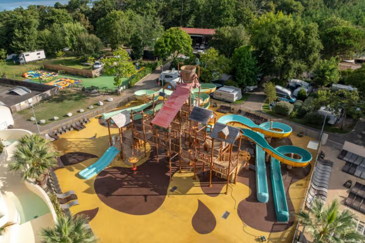 Aerial view of a playground with water slides and a campsite in the background.