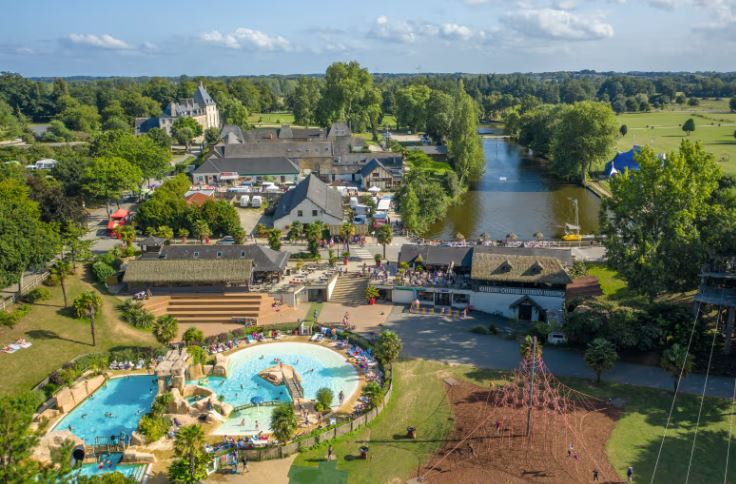 Aerial view of Domaine des Ormes in Brittany, France, showing a campsite with a pool, restaurants, and a lake.