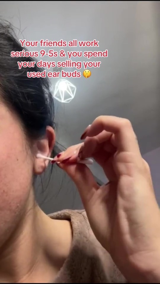 Person cleaning their ear with a cotton swab.