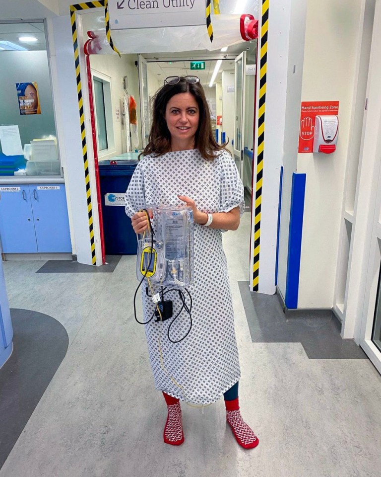 Woman in hospital gown holding medical equipment.