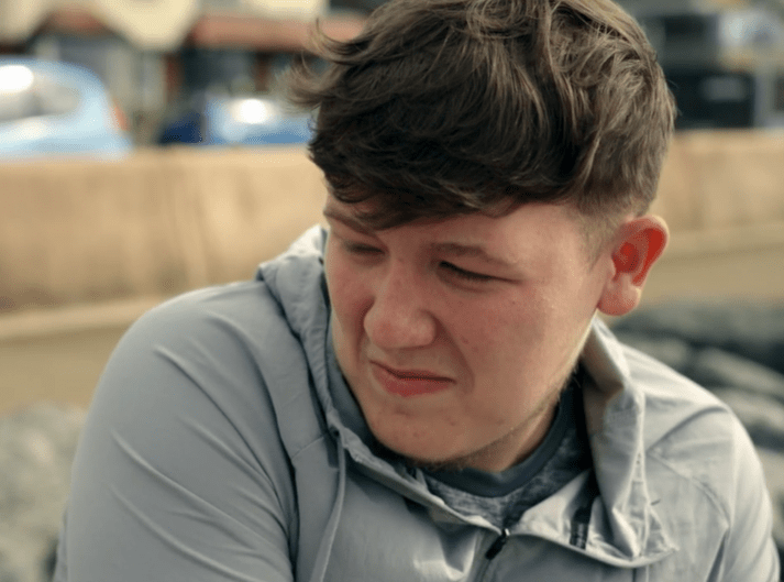 Close-up of a young man looking down, appearing upset.