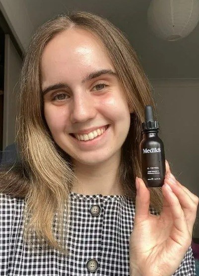 Woman holding a bottle of Medik8 G-Tetra serum.