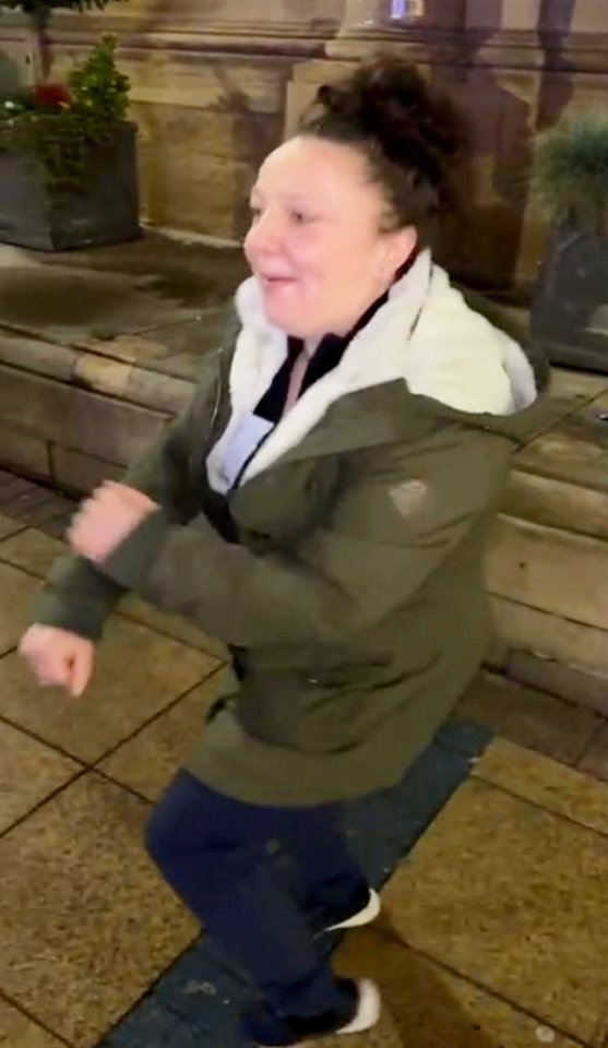 Woman in a green jacket dancing outdoors.