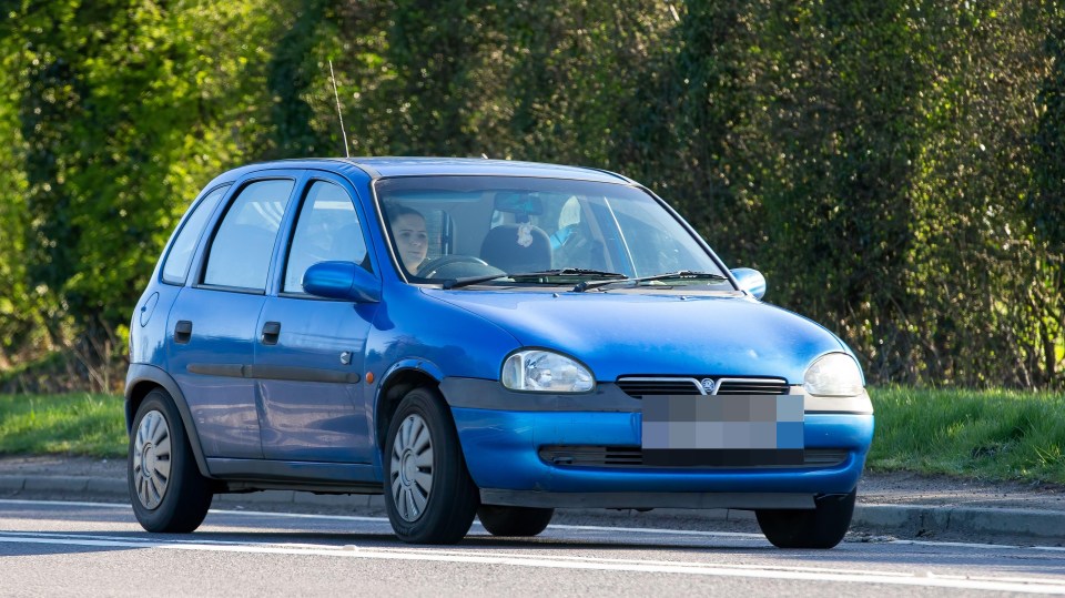 Blue Vauxhall Corsa driving on a road.