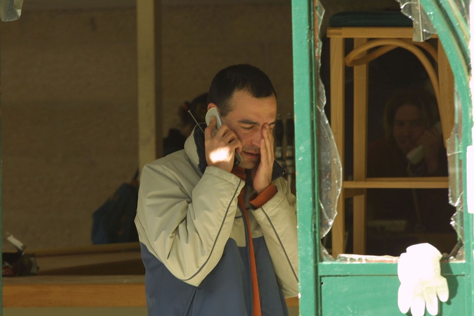 A cafe owner cries while talking on a cell phone outside his damaged cafe.