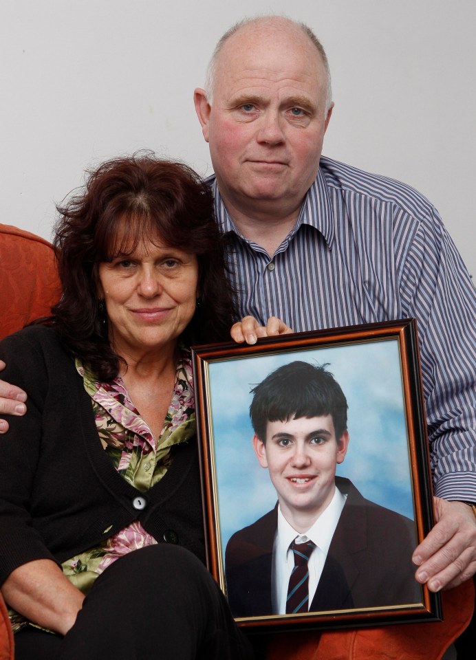 Parents holding framed photo of their murdered son.