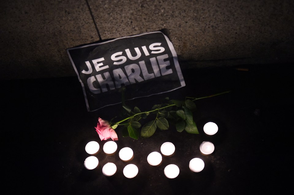 Candles, a rose and a sign are placed on the ground as people hold a candle lit vigil at the Old Harbour in Marseille in 2015