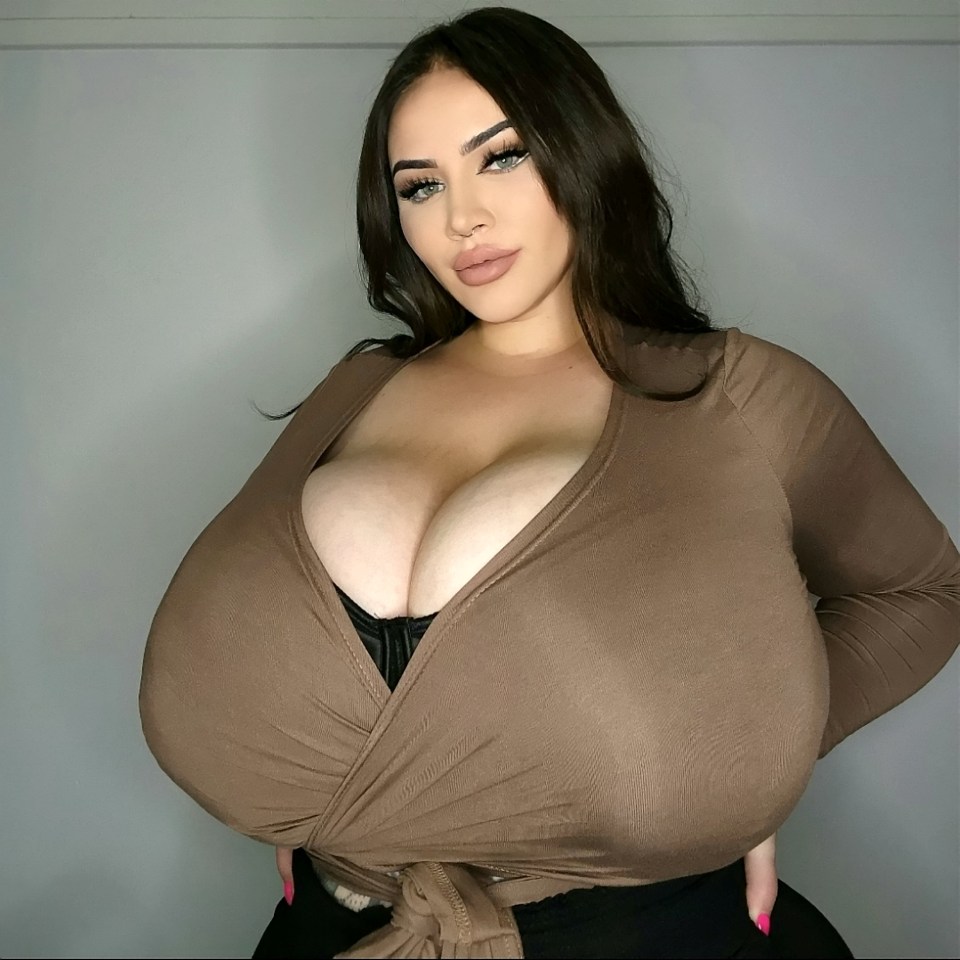 Woman with large breasts wearing a brown top.