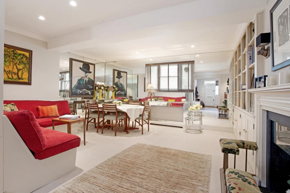 Interior view of a living and dining area with mirrored walls, red sofa, and dining table.