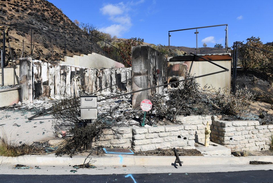 Fire-damaged remains of a house, with a Buddha statue and sundial still standing.