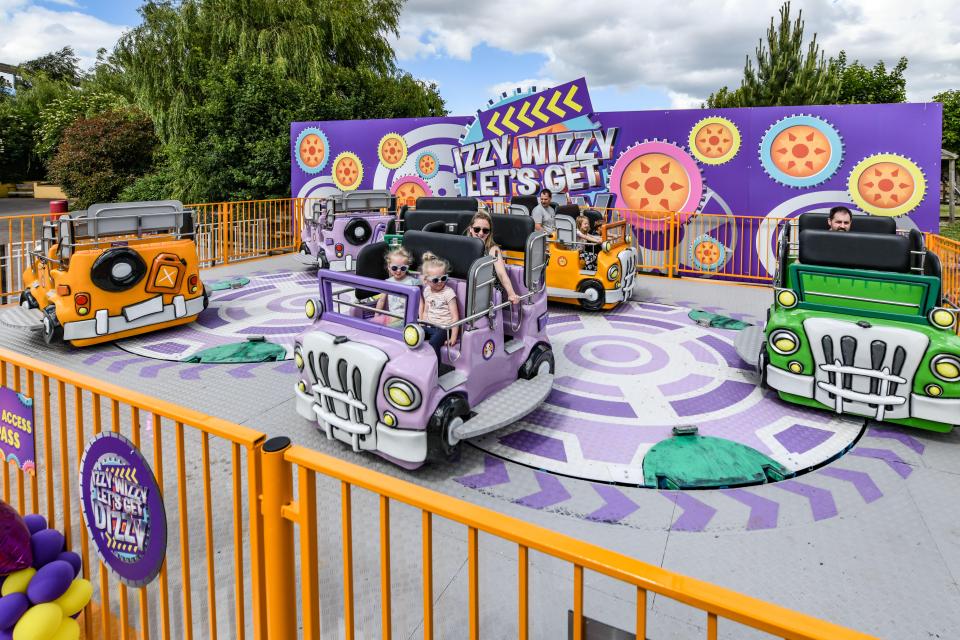 Families ride a spinning car attraction at a theme park.