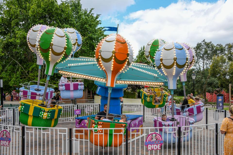 Children ride a hot air balloon-themed carousel.