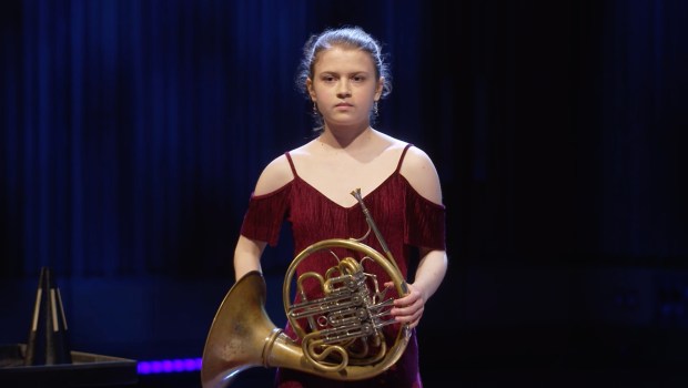 Young woman holding a French horn.