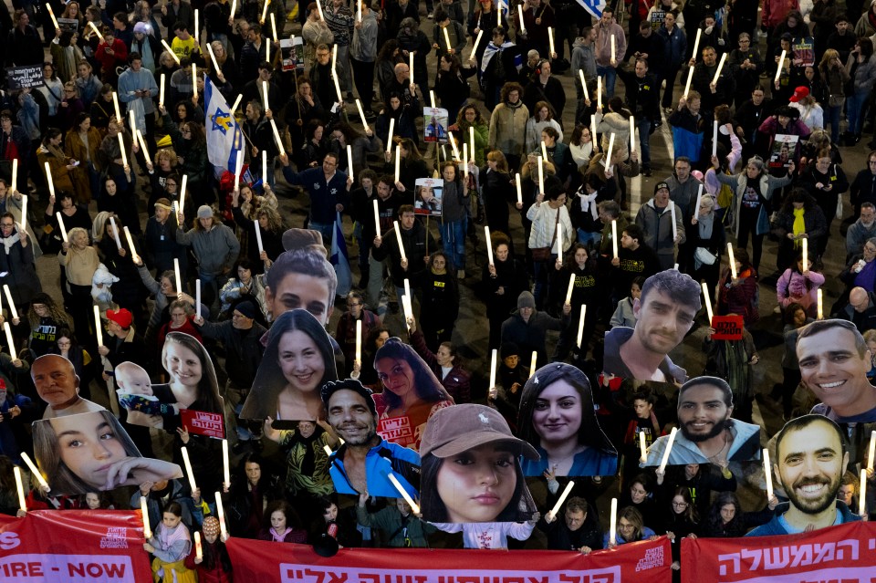 Protestors holding photos of hostages and lit sticks, demanding a hostage deal.