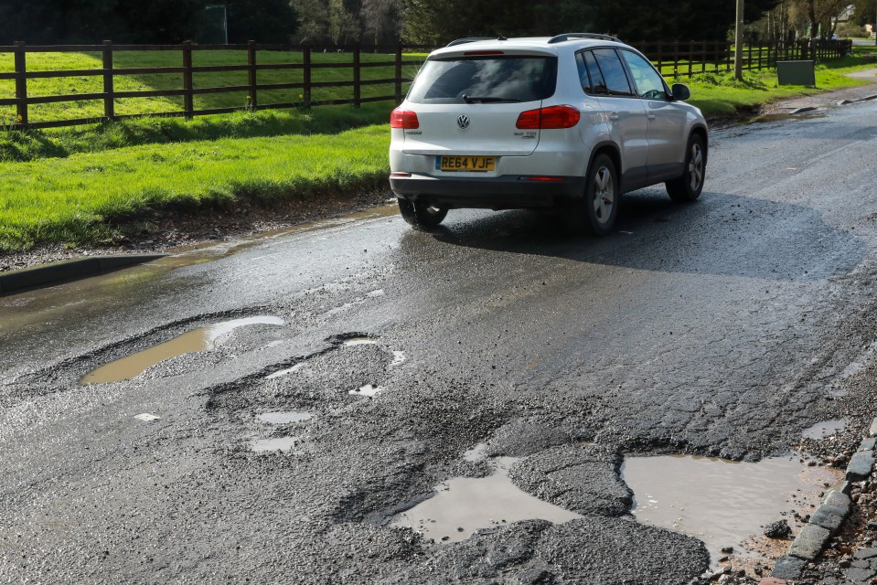 Car driving on a road with large potholes.