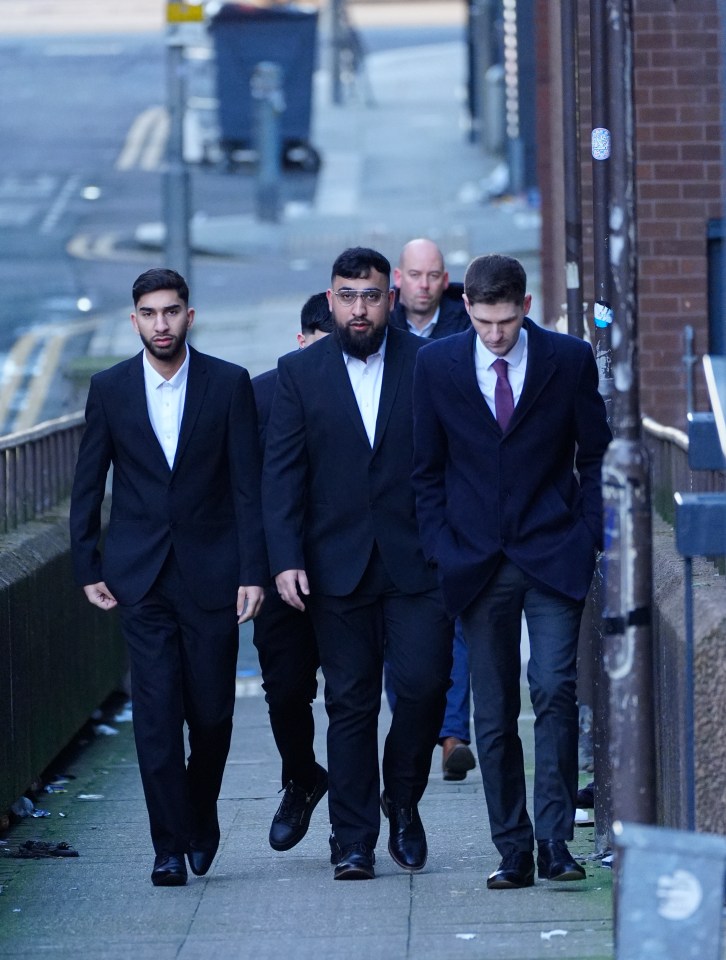 Three men in suits walking outside a courthouse.