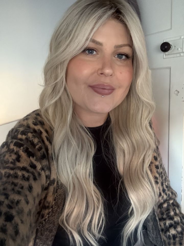 Portrait of a blonde woman wearing a leopard print cardigan.