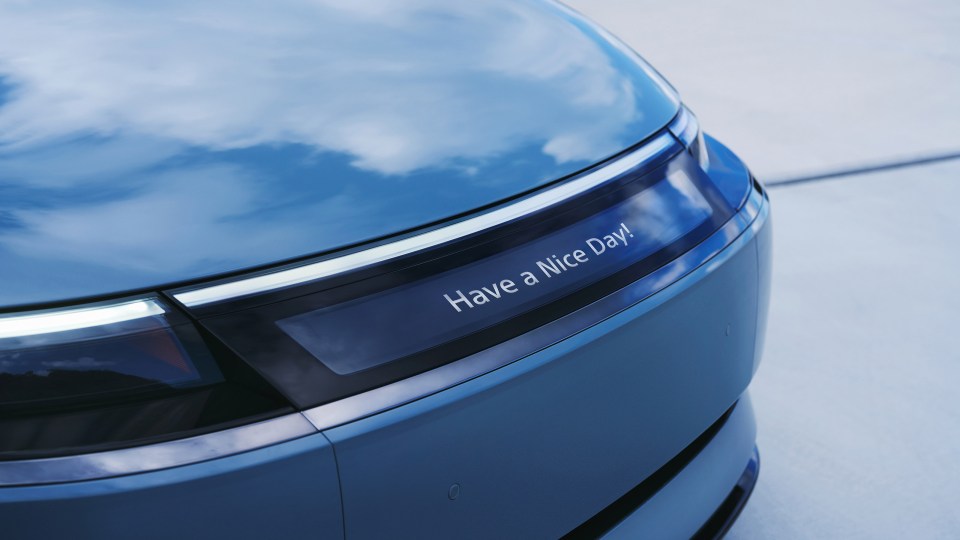 A blue car's front bumper displays "Have a Nice Day!"