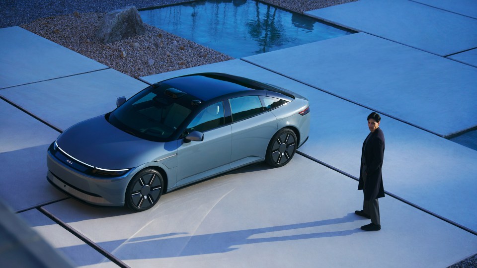 Afeela electric vehicle and a man standing on a patio.