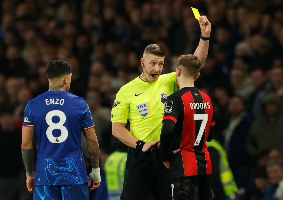 Referee showing David Brooks a yellow card during a soccer match.