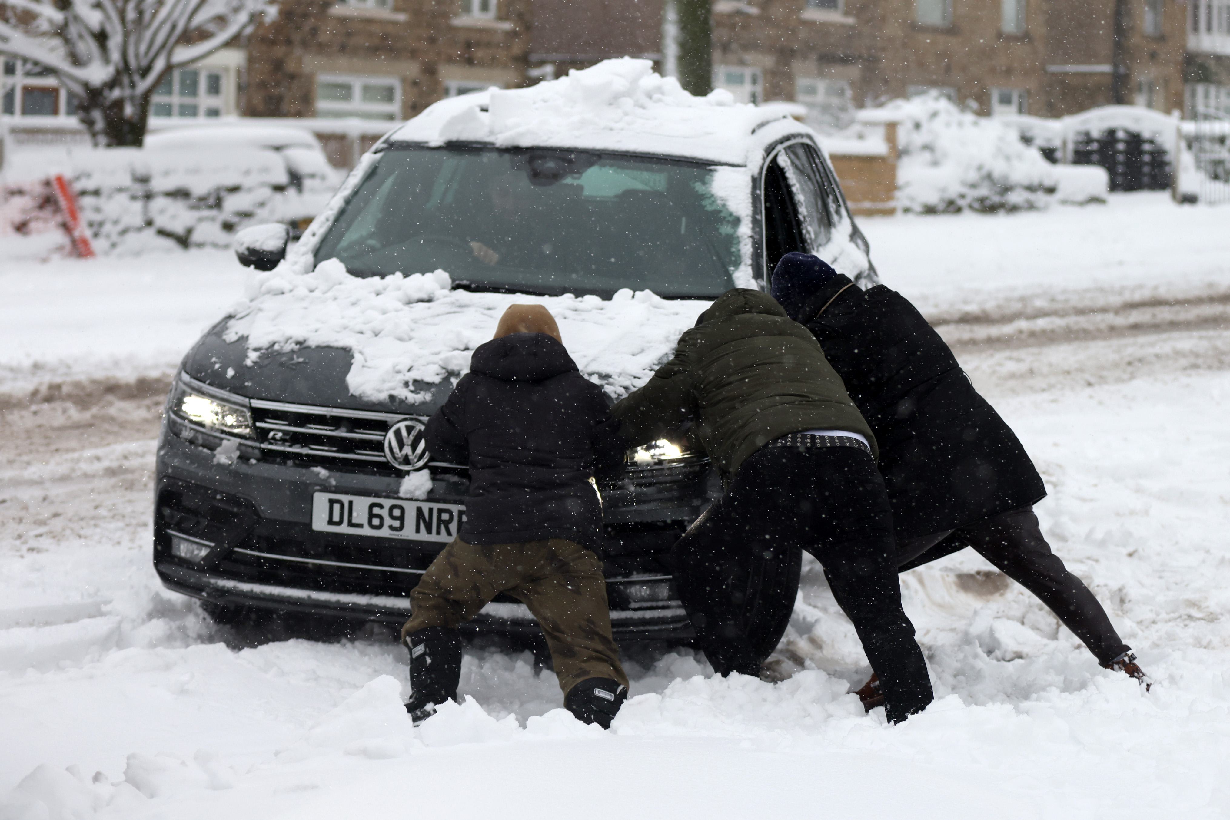 People help push a stranded car on January in Bradford this morning