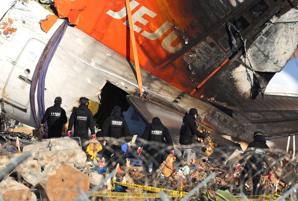 Police officers inspecting the wreckage of a crashed Jeju Air passenger plane.