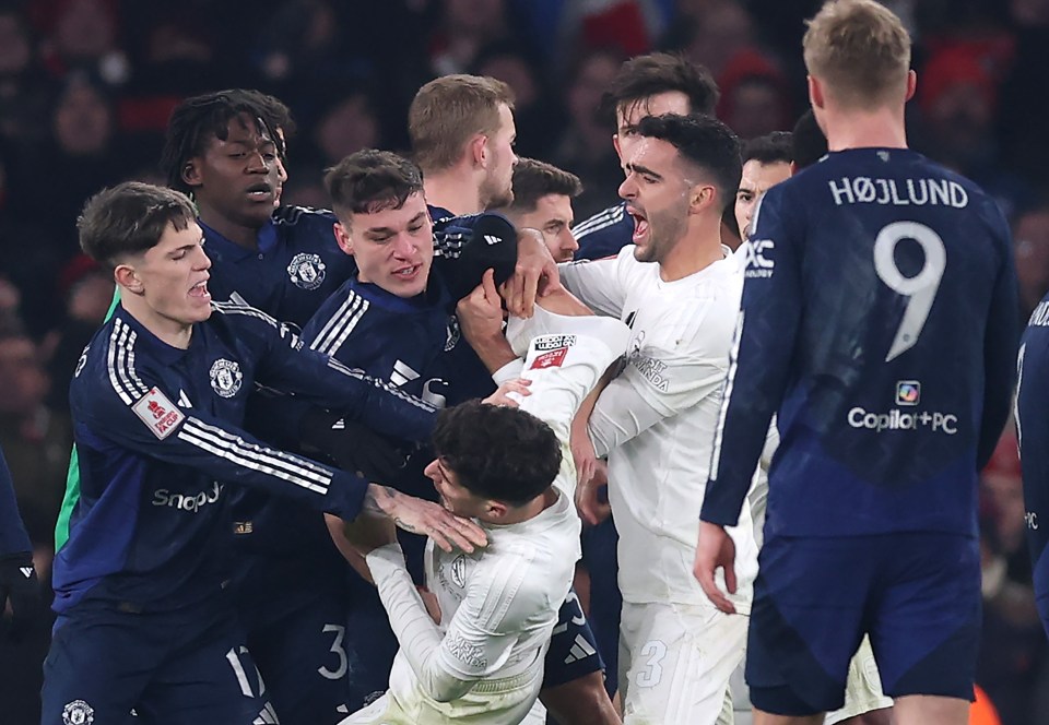 Arsenal and Manchester United players in a scuffle during a soccer match.