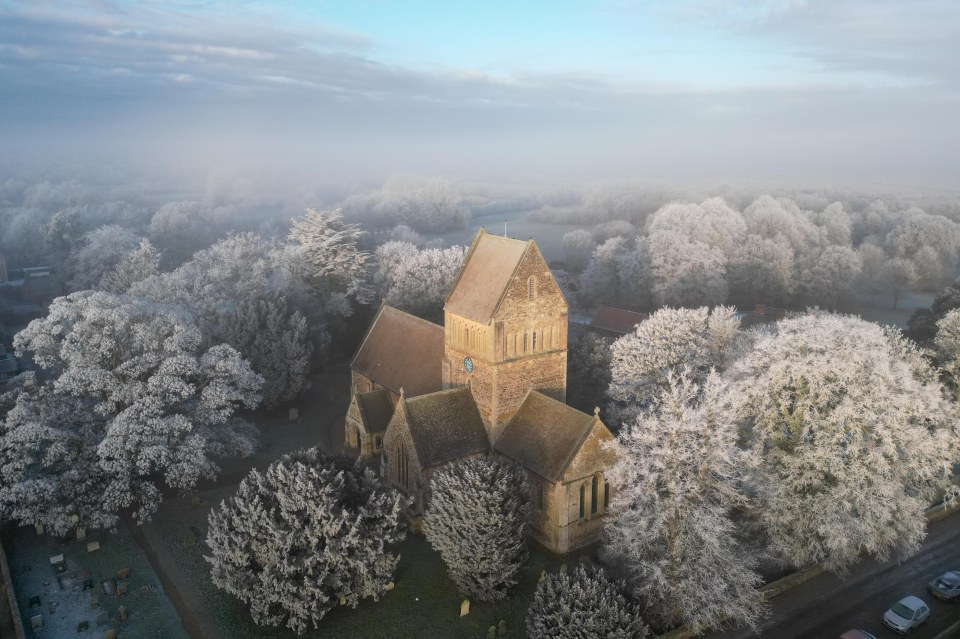 Aerial view of a frost-covered church and trees.