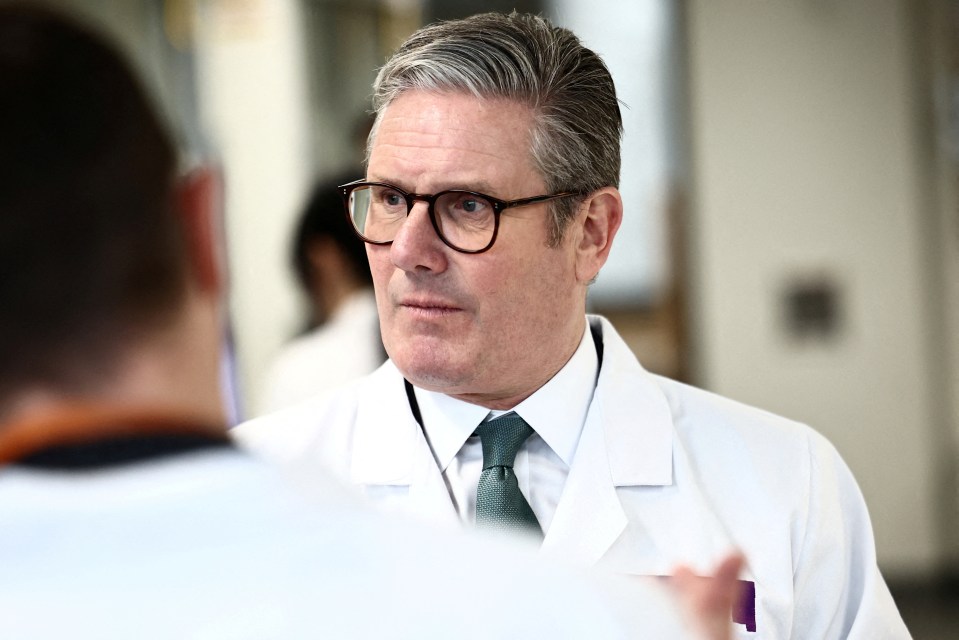 Keir Starmer speaking with researchers at a lab.