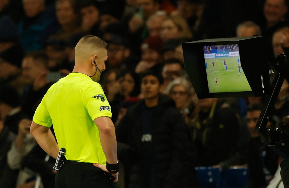 Referee reviewing a soccer play on the VAR monitor.