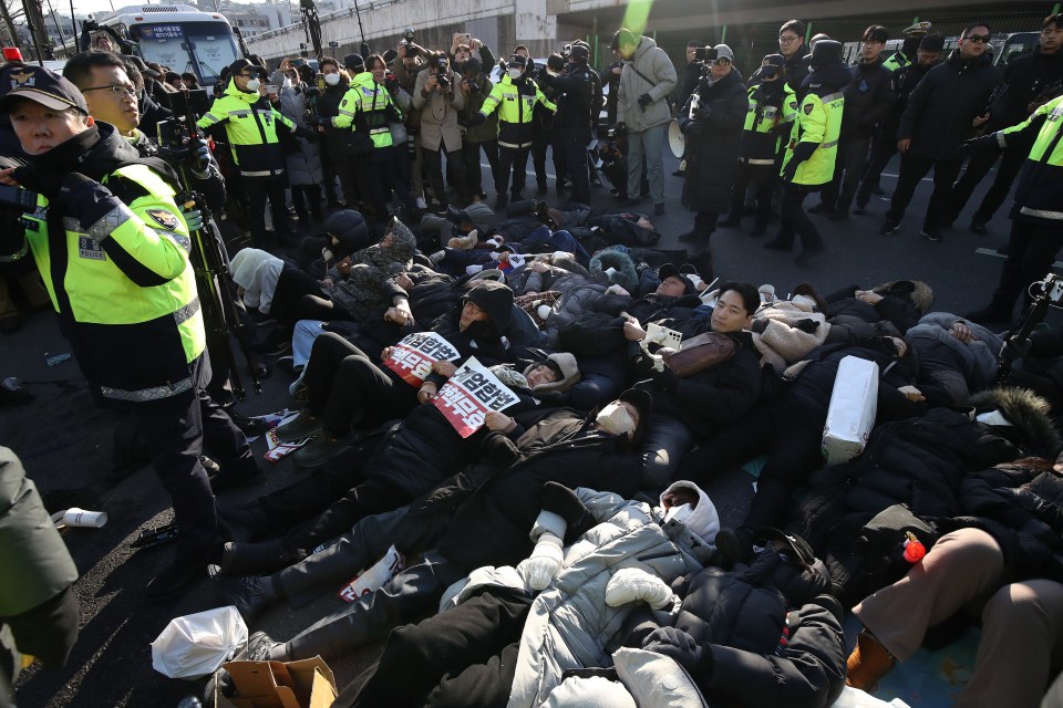 Pro-Yoon supports lie on the ground outside his residence after a warrant for his arrest was granted