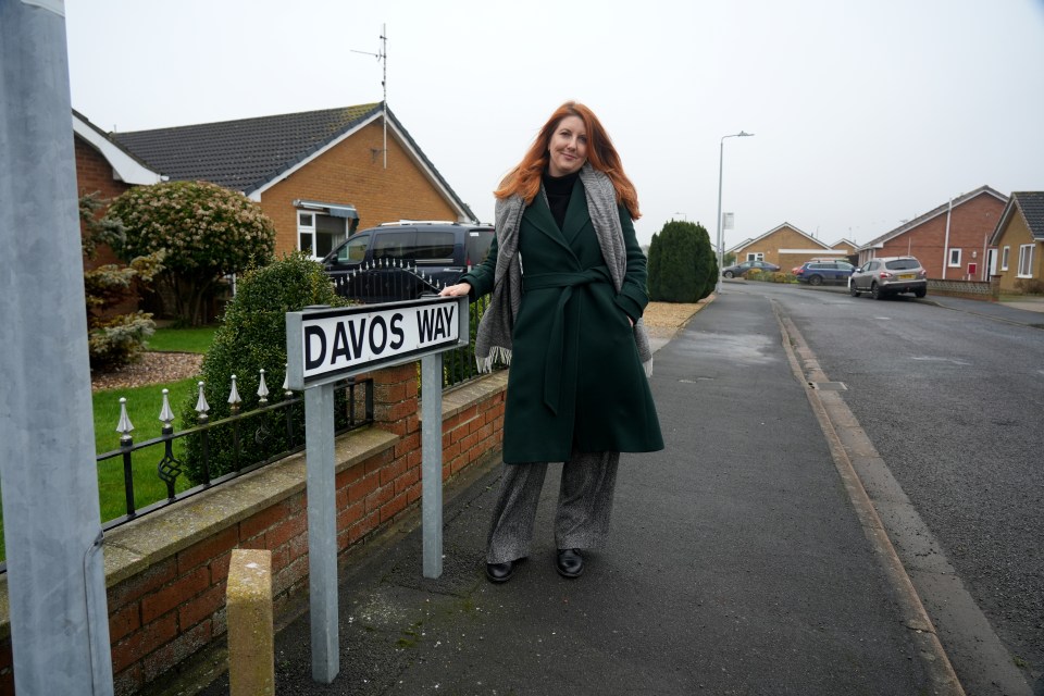 A woman stands by a Davos Way street sign.