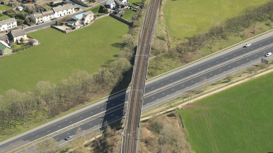 Aerial view of railway tracks crossing a motorway.