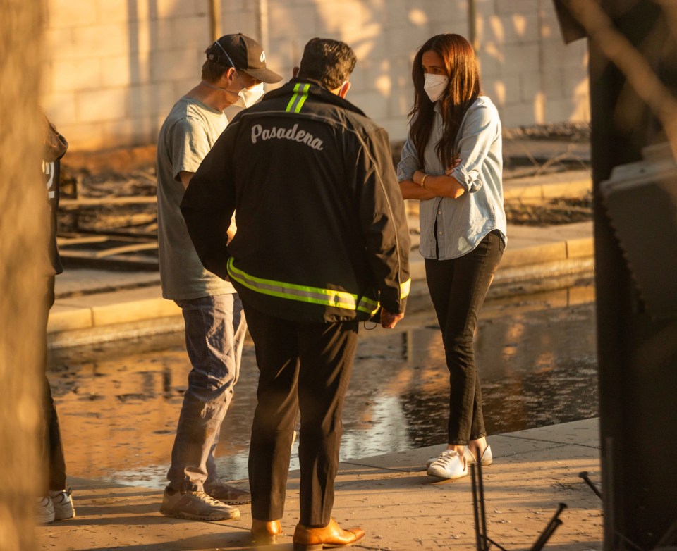 Meghan Markle speaking with officials at a fire-damaged site.