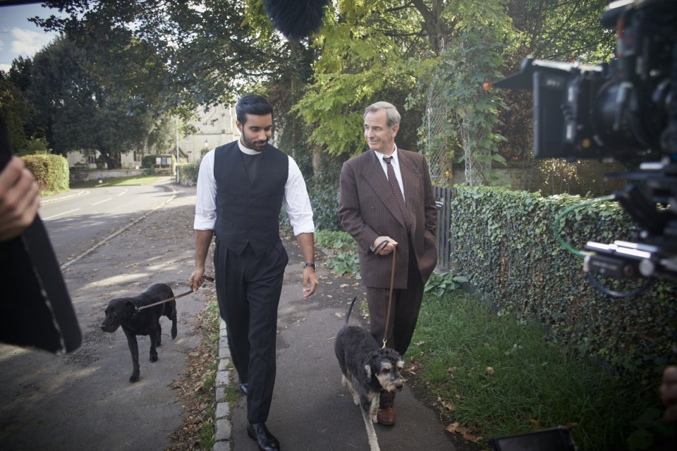 Two men walking dogs on a street, being filmed.