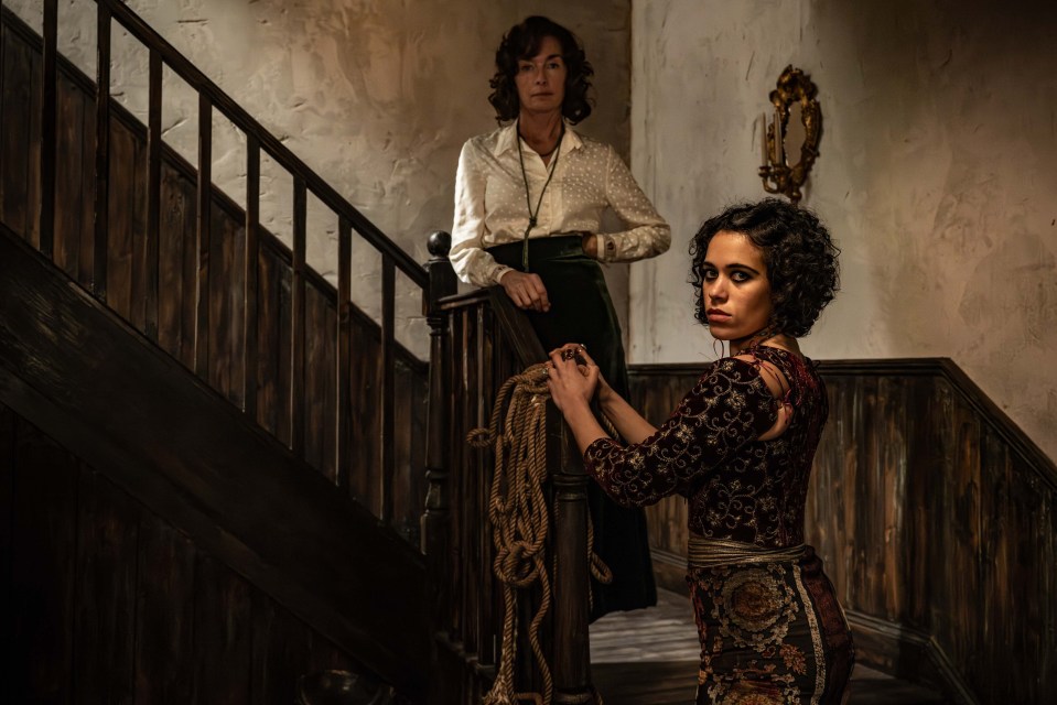 Two women on a staircase, one holding a rope.