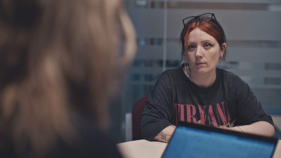 Woman with red hair in a police station assisting with inquiries.