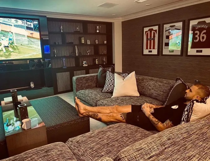 Kyle Walker relaxing on a couch in his home theater, watching a soccer game.