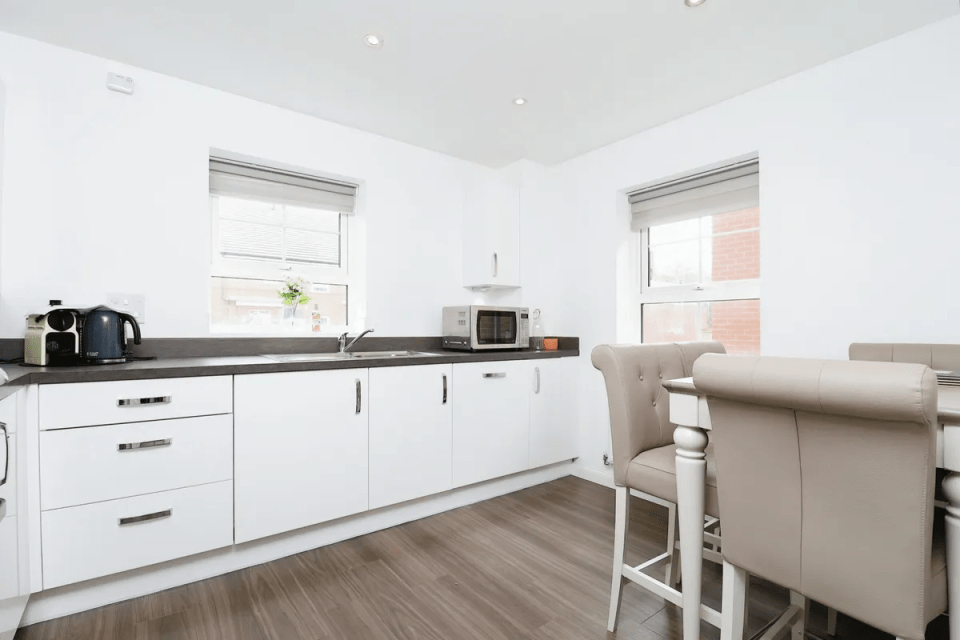 Modern kitchen with white cabinets and beige dining chairs.