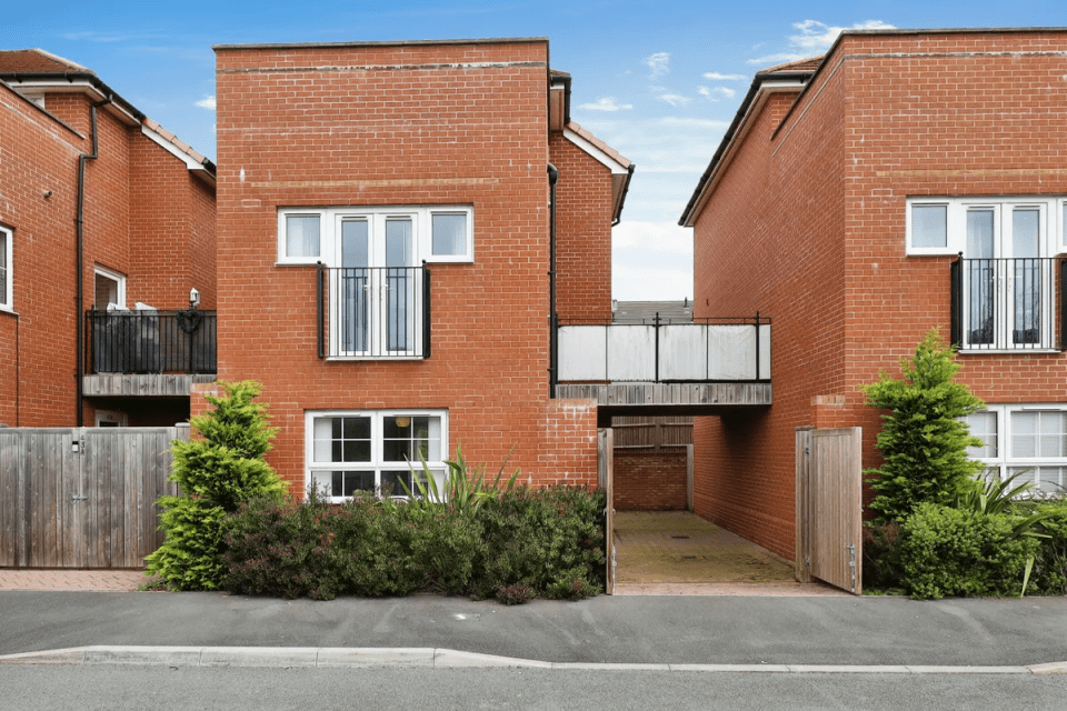 Brick townhouse for sale with an unusual covered walkway.