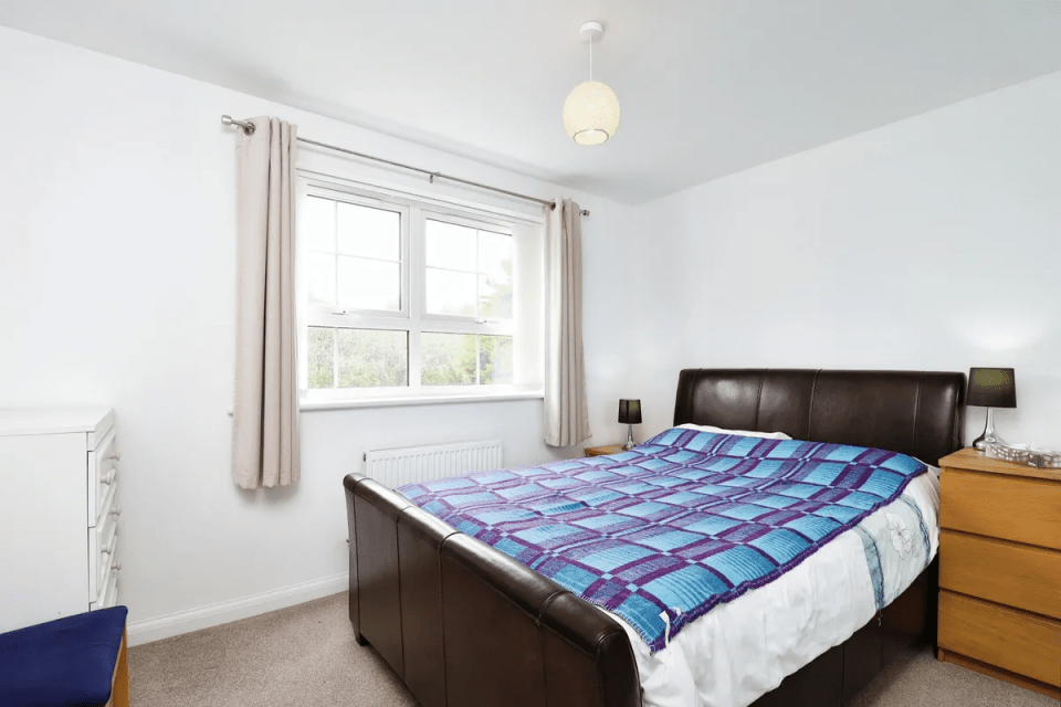 Bedroom with a brown leather bed and purple and blue blanket.