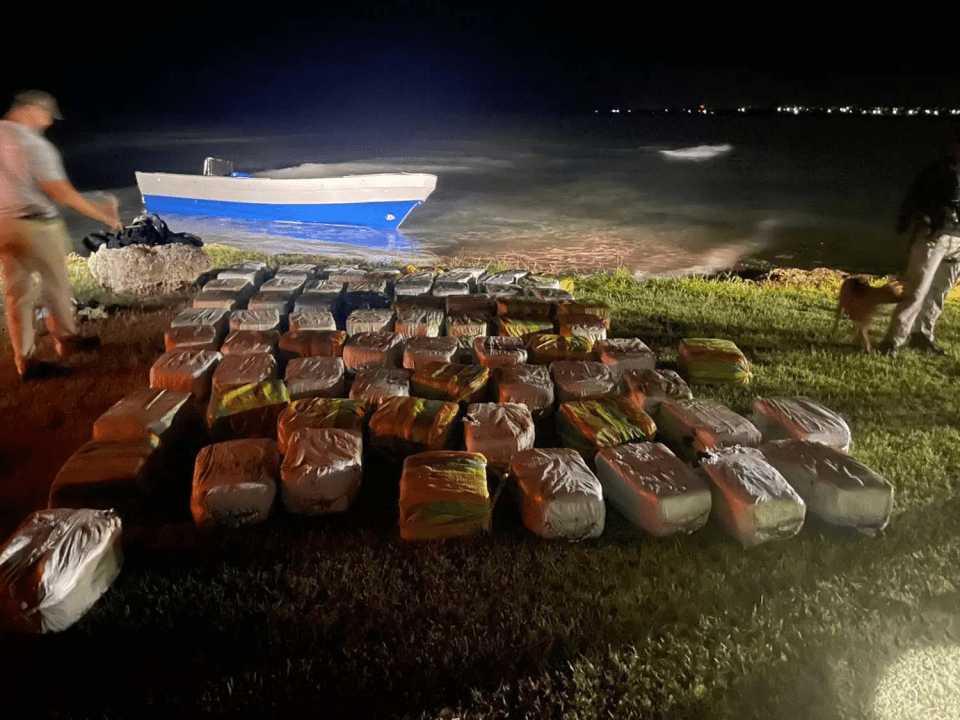 Seized cocaine packages near a boat at night.