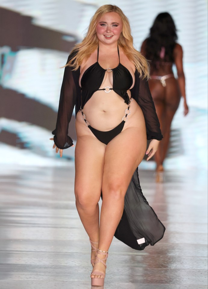 Model in black swimsuit walking a runway.