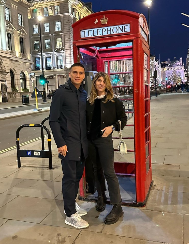 Couple posing by a red telephone booth in London.