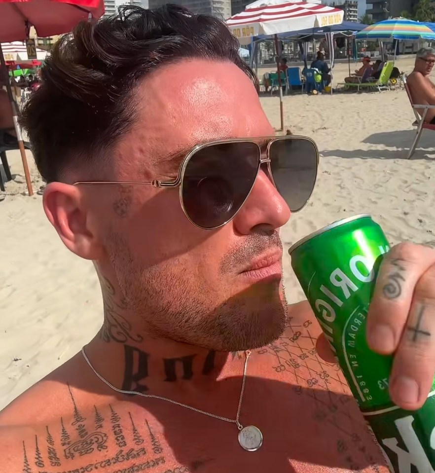 Man on beach drinking from a can.