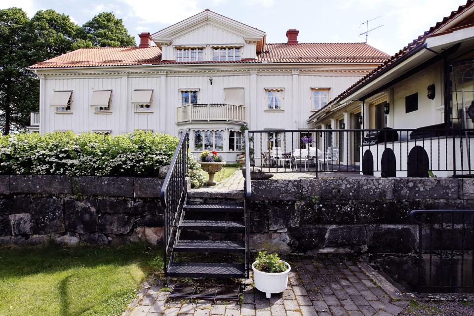 A white mansion with a red tile roof and a patio with outdoor furniture.