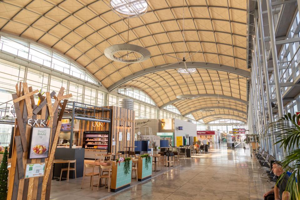 Alicante-Elche Airport interior with shops and seating.