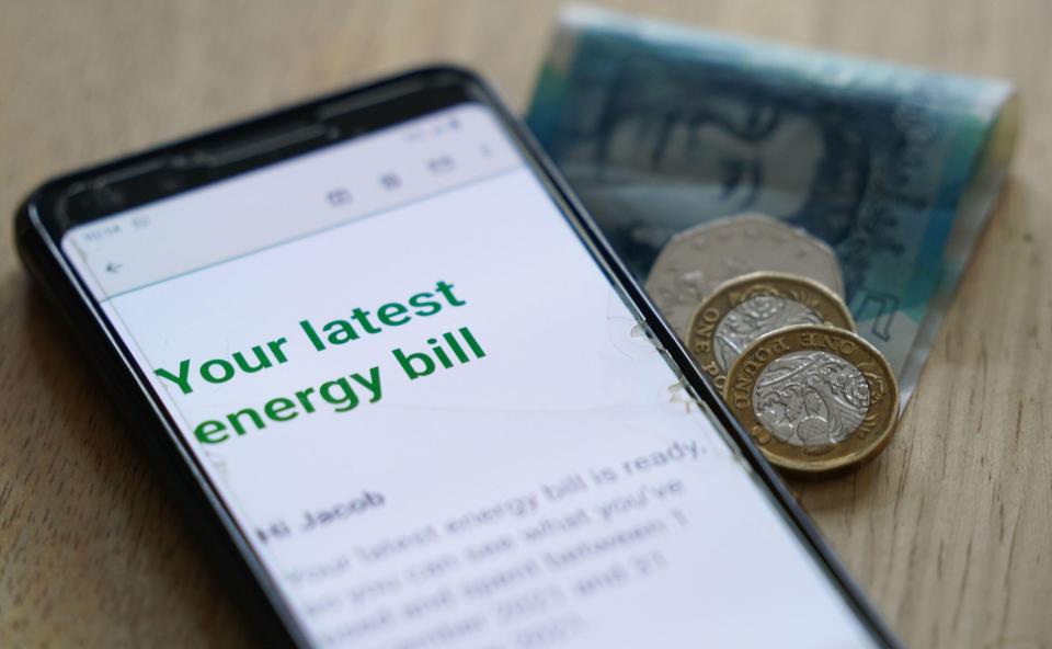 Smartphone displaying an online energy bill next to British currency.